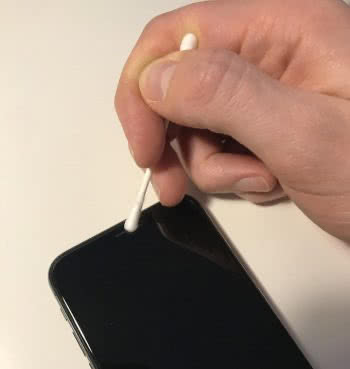 قم بتنظيف مكبر صوت iPhone باستخدام قطعة قطن.