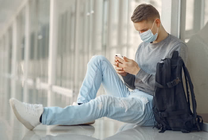 Man with face mask holding an iPhone